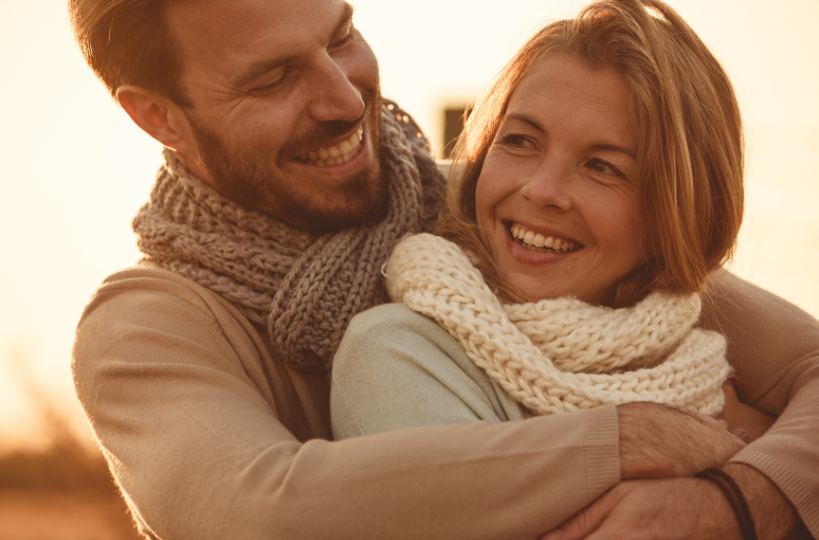 happy couple smiling and embracing during the sunset set outside