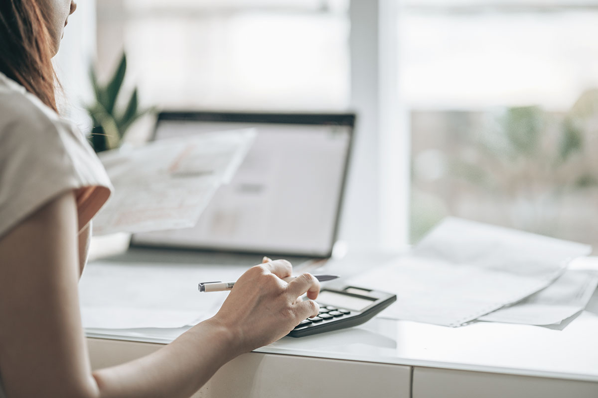 woman typing on calculator doing taxes at her desk
